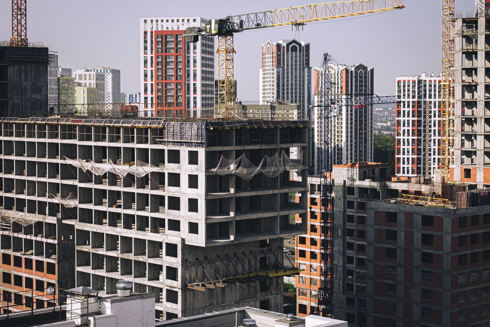 High-rise buildings under construction with tower cranes in a cityscape.